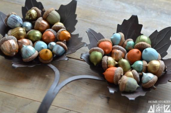 Colorful fall decor inspiration with decorative metallic acorns in autumn colors fill leaf-shaped metal bowls on a wooden table, creating a festive, warm, and rustic atmosphere.