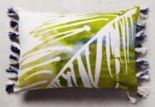 11 Easy decorative Handmade Appealing Printed Pillow Ideas A rectangular pillow with an abstract leaf pattern in green and white, featuring blue tassels on the sides. The design is fresh and vibrant.