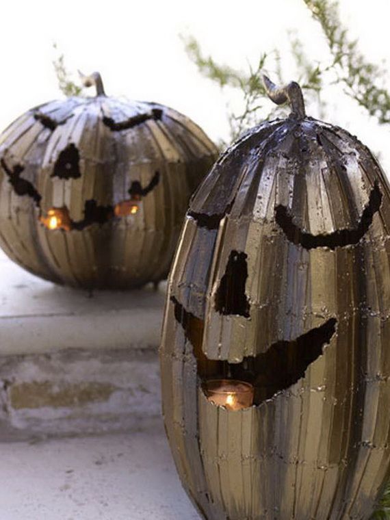 Two metallic jack-o'-lanterns with grinning faces glow warmly, illuminated by candles inside. They rest on steps, evoking a playful Halloween atmosphere.
