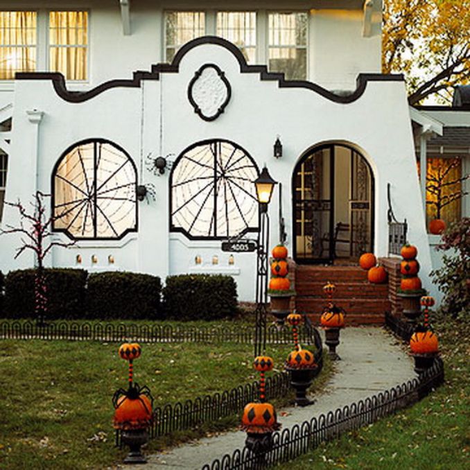 Festive Halloween-decorated house with spiderweb windows, pumpkins lining the path, and a spooky, inviting atmosphere under a soft evening glow.