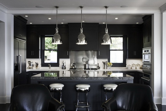 Sleek modern kitchen with black cabinetry and a marble countertop island. Three metallic pendant lights hang overhead. Black chairs provide seating.