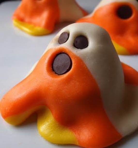 Colorful ghost-shaped candies with chocolate eyes and an open mouth. They have a playful, Halloween theme with orange, yellow, and white layers.
