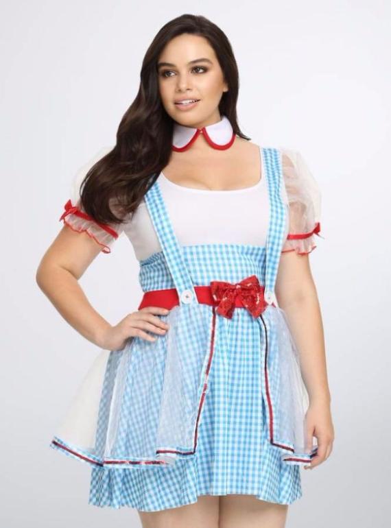 Woman smiling in a blue gingham dress with a red bow and white puff sleeves. She wears a white undershirt and a red-trimmed collar, exuding a playful tone.