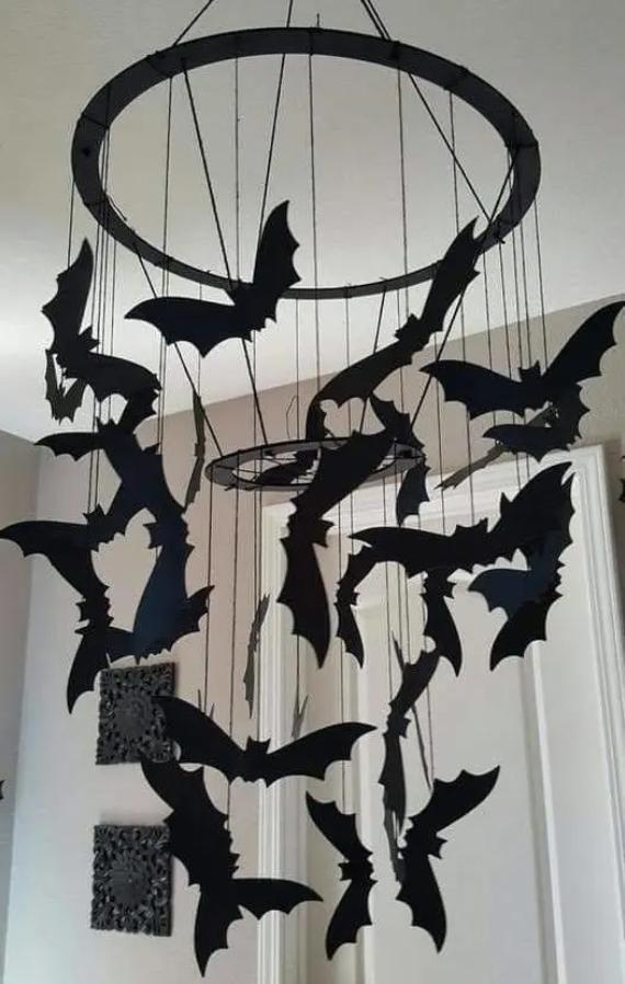 A mobile with black bat silhouettes hangs from the ceiling, creating a spooky, Halloween-themed decoration against a white wall backdrop.